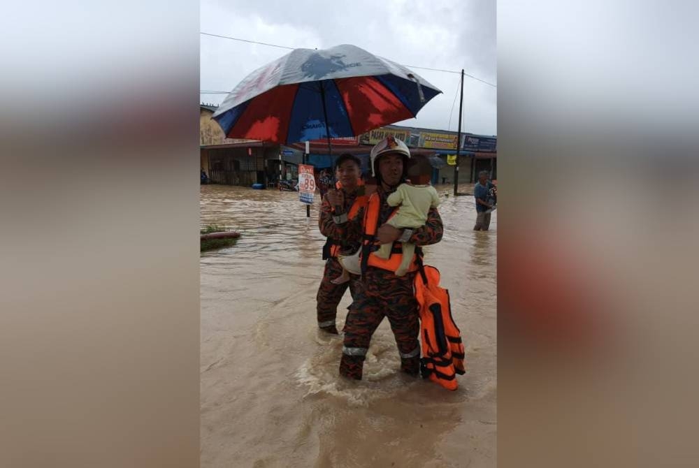 Anggota bomba bersama salah seorang daripada tiga yang diselamatkan dalam insiden banjir kilat di kampung berkenaan. - Foto bomba