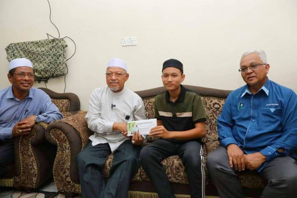 Ahmad (dua dari kiri) semasa menziarahi Muhammad Shahril di rumahnya di Bachok.