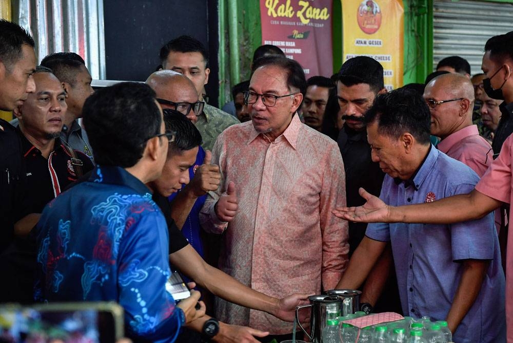 Anwar (tengah) beramah mesra bersama pengunjung pasar pada Majlis Temu Mesra Perdana Menteri di Pusat Penjaja Madani Jalan Tuanku Abdul Rahman Lestari Niaga@Kuala Lumpur di Chow Kit pada Khamis. - Foto: Bernama