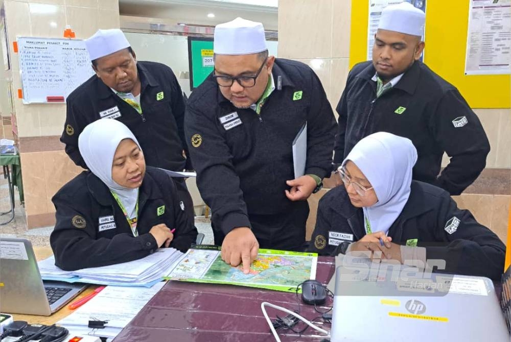 Mohd Zawawi (tengah) bersama pasukan beliau meneliti peta lokasi hotel menempatkan jemaah syarikat PJH di Tanah Suci.