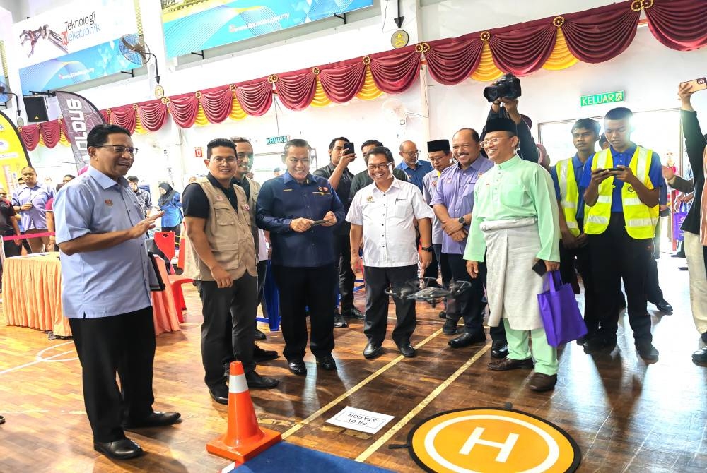 Mustapha (tiga dari kanan) melihat Aminuddin ( tiga dari kiri) mencuba dron ketika melawat Karnival Madani TVET di Institut Latihan Perindustrian Pedas pada Jumaat.