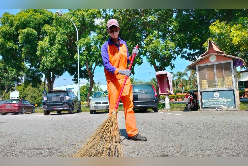 Danish Atib ketika melakukan kerja-kerja membersihkan kawasan rumah kedai di Cheng.