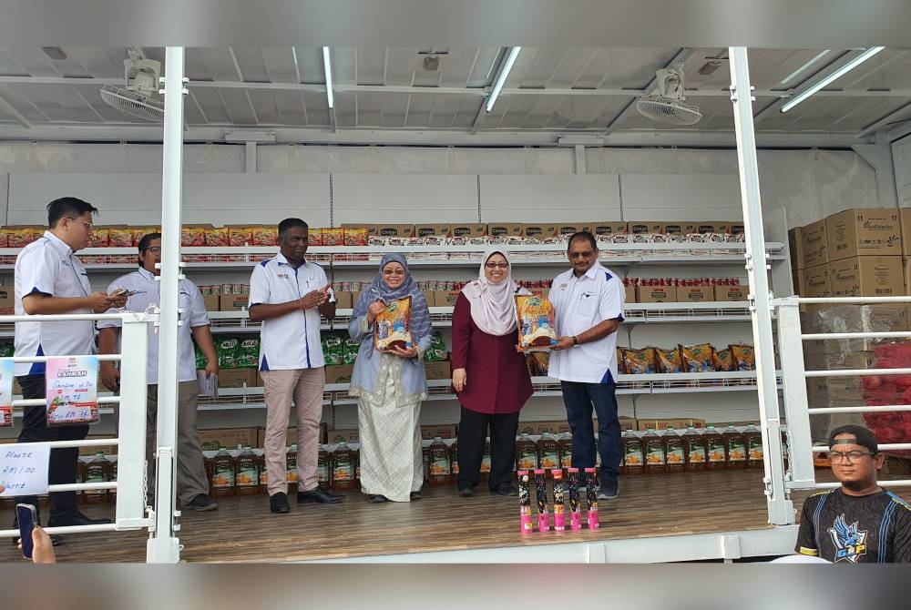 Fauziah (dua dari kanan) dan Norlela (tiga dari kanan) melakukan jualan lelong barangan keperluan harian di atas treler Jualan Rahmah bergerak sempena Love Penang Agrofest@Pesta Mengkuang 2023 pada Sabtu.