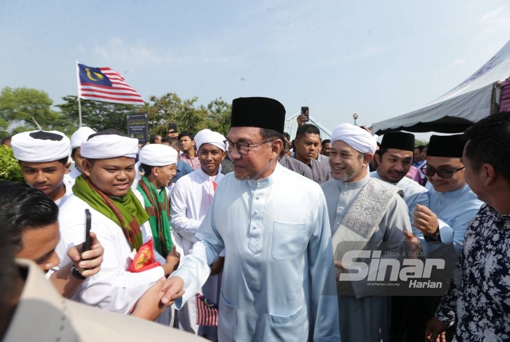 Anwar bersalaman dengan pelajar dan hadirin yang menyambut ketibaan beliau bagi menjayakan sambutan Jubli Intan SMA Nahdhah Hasanah Melele, Kodiang.