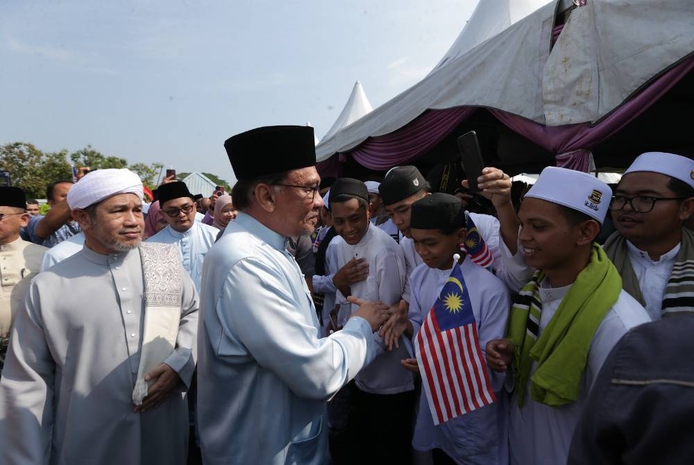 Anwar beramah mesra dengan pelajar sekolah agama yang menyambut ketibaan beliau di SMA Nahdhah Hasanah Melele, Kodiang, pada Sabtu.