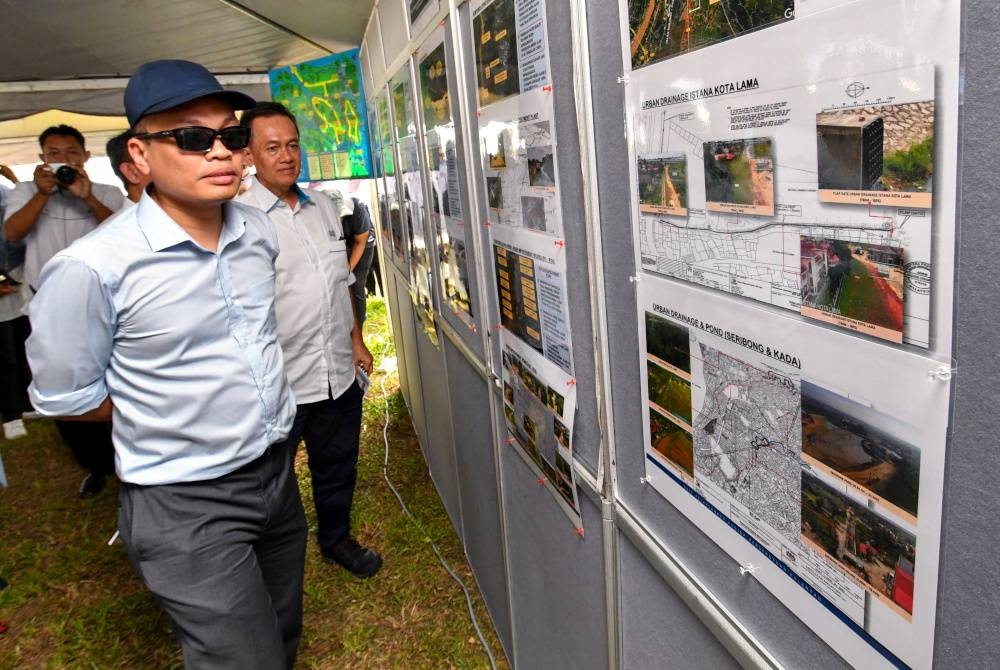 Nik Nazmi melihat pelan lokasi pembinaan ketika melakukan lawatan ke Projek Pembangunan Persekutuan di Pulau Teluk Renjuna pada Sabtu. - Foto Bernama