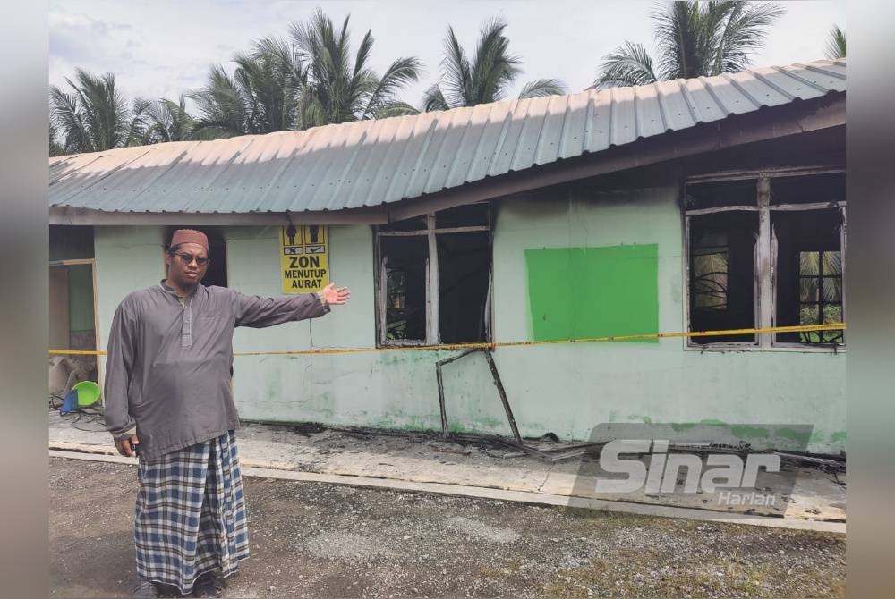 Mohd Anuar menunjukkan bangunan asrama sekolah itu terbakar pada Ahad.