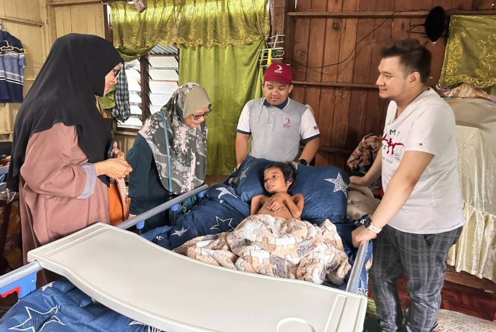 Ahmad Iqbal (kanan) bersama Mohd Khairul Ahmad (dua dari kanan) ketika menziarahi Muhammad Hafizuddin di Kampung Lorong Haji Da, di Kuala Terengganu, pada Isnin.