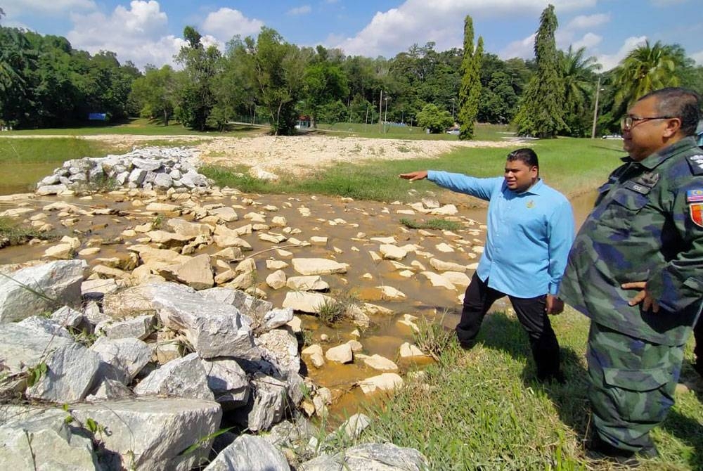 Muhamad Arafat (kiri) meninjau keadaan kolam tadahan di Pusat Latihan PGA Ulu Kinta pada Selasa.