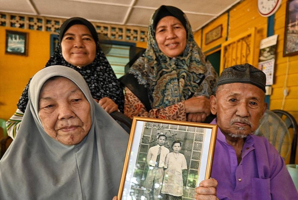 Zaleha (kiri) bersama dua orang anak dan suaminya menunjukkan gambar ibu bapa angkatnya ketika ditemui di rumahnya di
Kampung Tanjung Minyak pada Rabu.