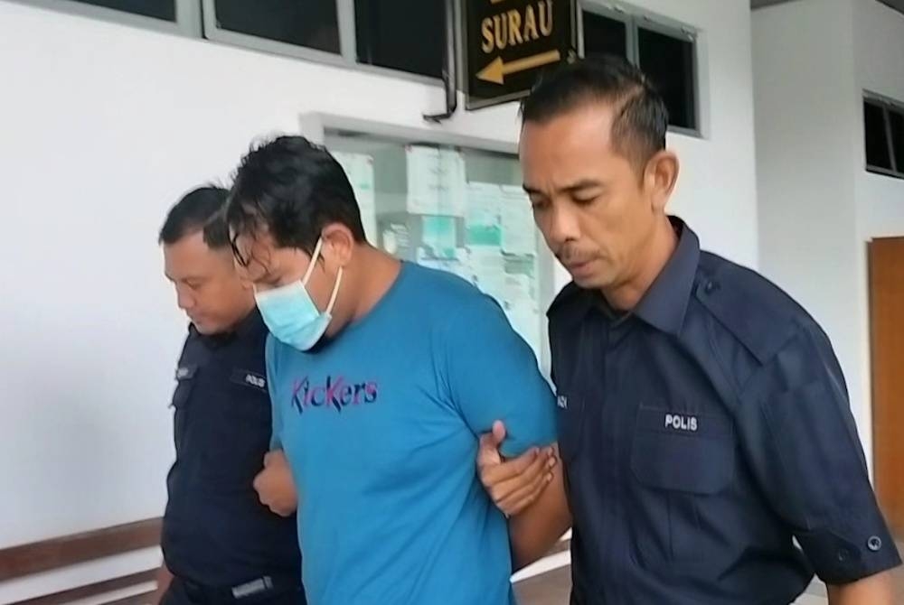 Azwan (dua dari kiri) ketika dibawa keluar dari Mahkamah Seksyen di Melaka pada Jumaat.