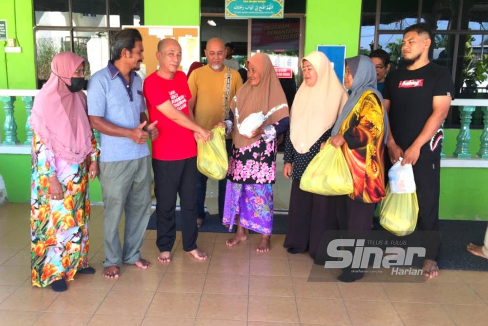 Muhamad Nizam (tiga dari kiri) menyampaikan sumbangan makanan kepada penerima di Chempaka, Kota Bharu pada Jumaat. - Foto Sinar Harian