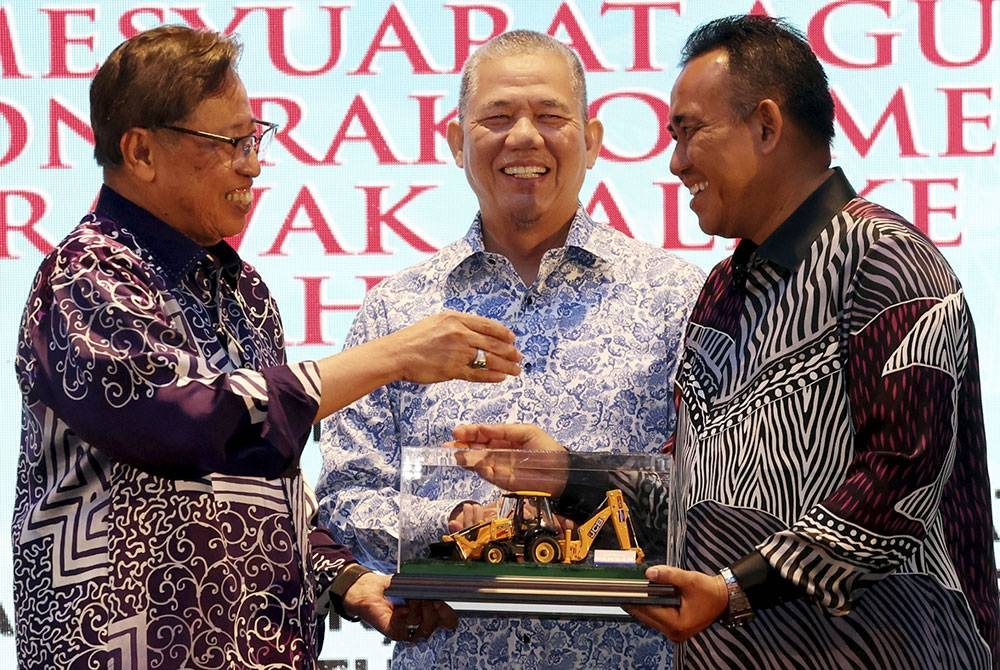 Abang Johari menerima model jentolak daripada Yang Dipertua PKMM Sarawak, Datuk Ismail Suut (kanan) pada majlis makan malam dan perasmian mesyuarat agung tahunan PKKM Sarawak kali ke-24, malam tadi. Foto Bernama