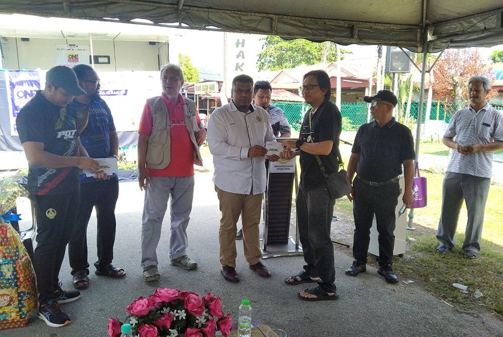 Muhamad Arafat (empat dari kiri) menyampaikan sumbangan kepada salah seorang mangsa ribut berhampiran Dewan Seri Delima, Kampung Tersusun Batu 5, Tambun di sini pada Sabtu.