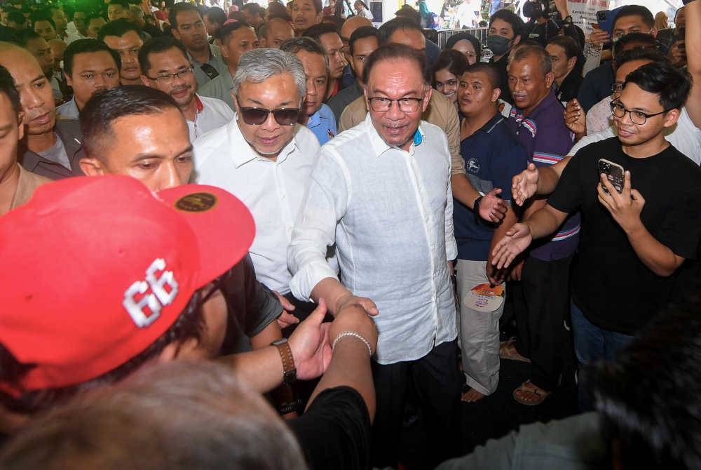 Perdana Menteri Datuk Seri Anwar Ibrahim bersama Timbalan Perdana Menteri Datuk Seri Dr Ahmad Zahid Hamidi yang juga Menteri Kemajuan Desa dan Wilayah bersalaman dengan orang ramai pada Majlis Pelancaran Sentuhan Kasih Desa di Dataran Nilai pada Sabtu. - Foto Bernama.