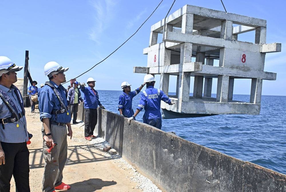 Adnan (dua dari kiri) melihat tukun tiruan yang diturunkan pada Program Melabuh Tukun Tiruan Penghalang Pukat Tunda Juvenil (Konservasi) di perairan Pulau Kapas pada Ahad. - Foto: Bernama