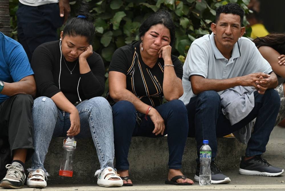 Ahli keluarga yang maut dalam kejadian tembakan menunggu di luar stesen polis Ecuador. - Foto AFP