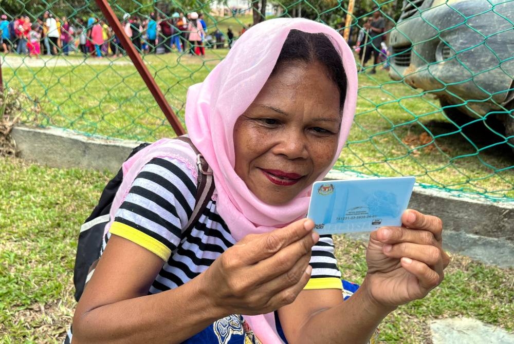 Penduduk Orang Asli suku kaum Temiar, Ajah Adik, 48, melihat kad pengenalan yang baharu sahaja diterima daripada wakil Jabatan Pendaftaran Negara (JPN) sempena Program Outreach dan Kembara Mesra Rakyat di Pos Belatim, pada Isnin. - Foto Bernama