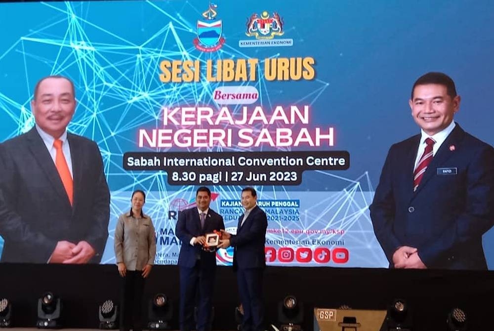 Rafizi menerima cenderahati daripada Shahelmey ketika sesi libat urus bersama kerajaan negeri Sabah di SICC, Kota Kinabalu.