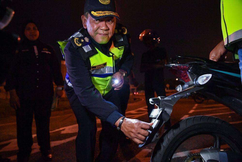 Khairul Khar (tengah) mengukur plat pendaftaran sebuah motosikal ketika Operasi Hari Raya Aidiladha 2023 Peringkat Selangor di Plaza Tol Petaling Jaya Selatan pada malam Selasa. - Foto: Bernama