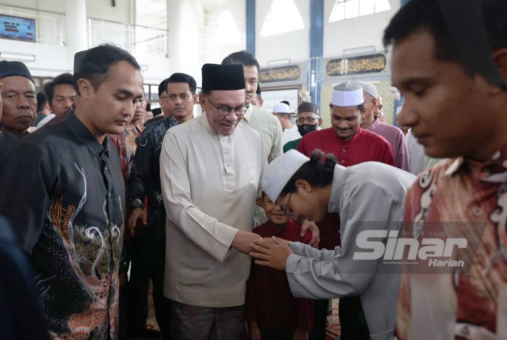 Anwar bersalaman dengan orang ramai ketika hadir kenduri korban dan solat Jumaat di Masjid Jamek An-Nur, Kampung Guar Perahu pada Jumaat.