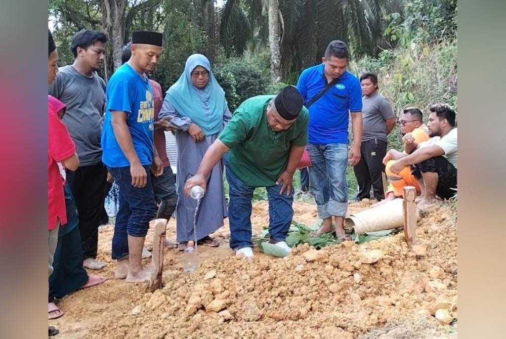 Jasni menyiram air di pusara Allahyarham Muhammad Zaihan di Tanah Perkuburan Islam (Tinggi), Kampung Ladang, Iskandar Puteri pada Jumaat.