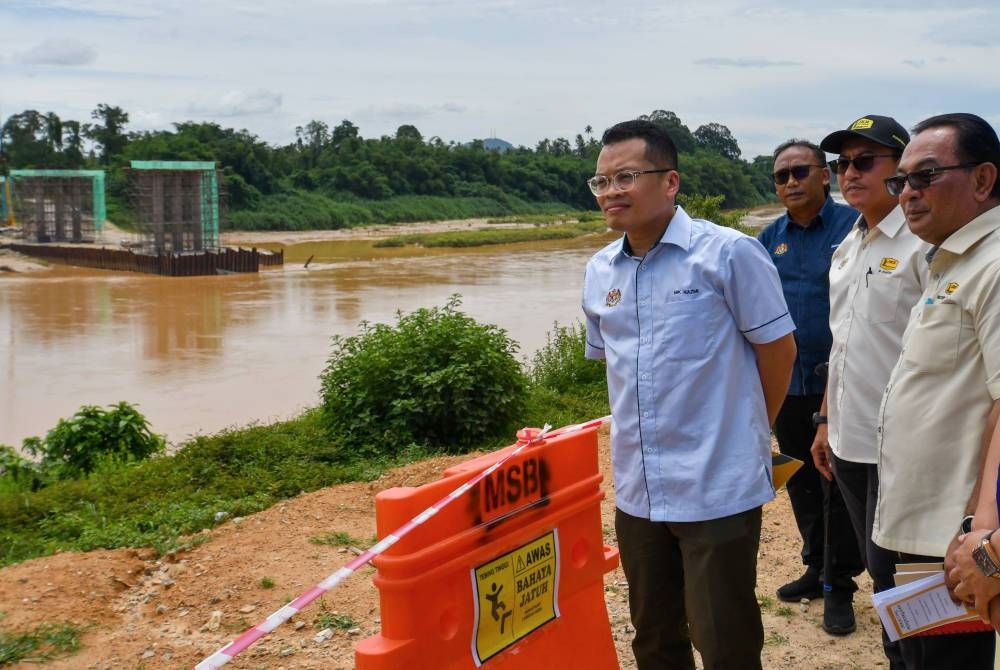 Nik Nazmi (kiri) ketika melakukan lawatan ke tapak Projek Pembinaan Jalan dan Jambatan Kampung Joh ke Kampung Belimbing, Tanah Merah hari ini. - Foto Bernama