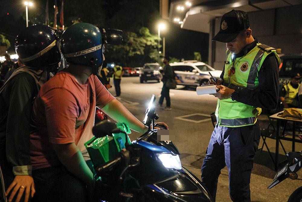 Anggota JPJ Kuala Lumpur mengeluarkan saman kepada pengguna jalan raya yang melanggar undang- undang pada Operasi Khas Aidiladha Siri 2/2023 di Jalan Pahang pada Ahad. - Foto Bernama