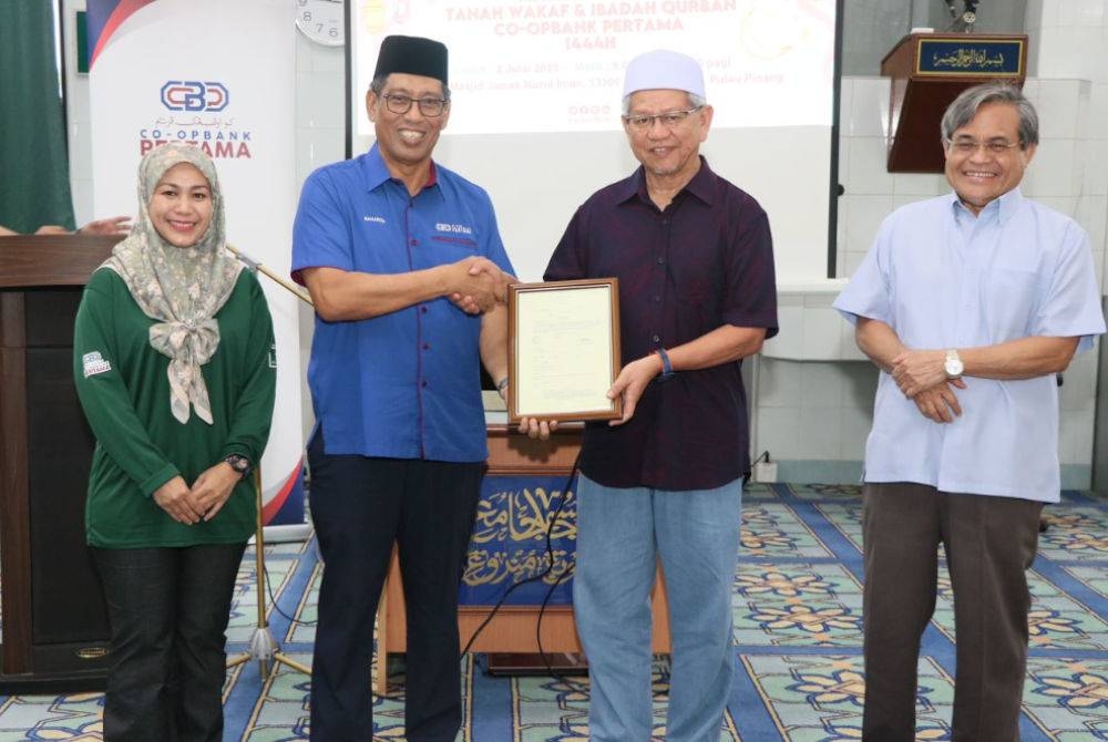 Baharom (dua dari kiri) menyerahkan geran tanah wakaf Masjid Jamek Nurul Iman Kubang Menerong dan Surau Ad Diniah Kampung Lembah Raja kepada Ahmad Zakiyuddin.