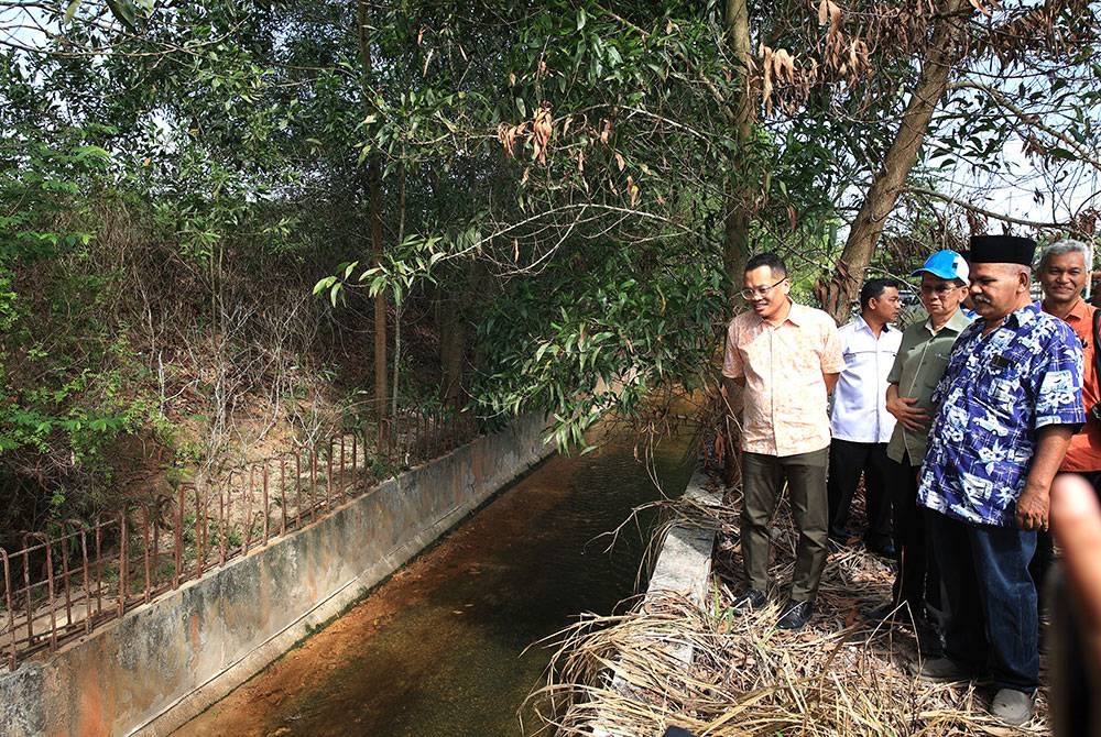 Nik Nazmi (kiri) melawat dan melihat keadaan saliran di Taman Wadi Iman, Kok Lanas di Kota Bharu.