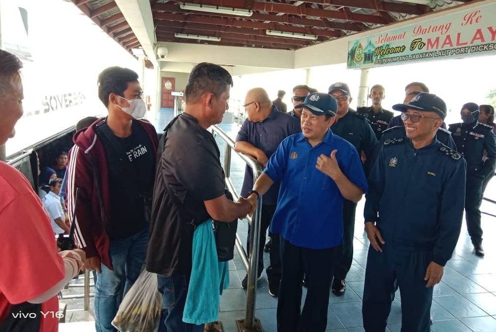 Ahmad (dua dari kanan) beramah mesra dengan pelancong dari Dumai, Indonesia di Jeti Penumpang di Port Dickson pada Selasa.