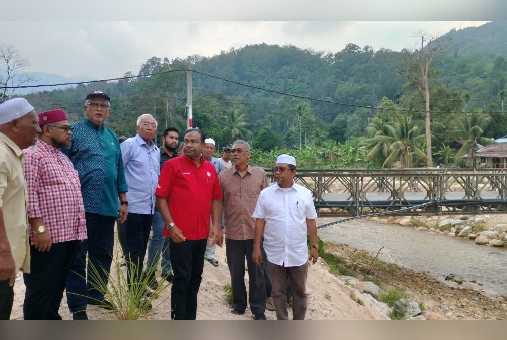 Mahdzir (empat dari kiri) meninjau keadaan lokasi kejadian banjir aliran puing di Kampung Iboi, Baling pada Selasa.