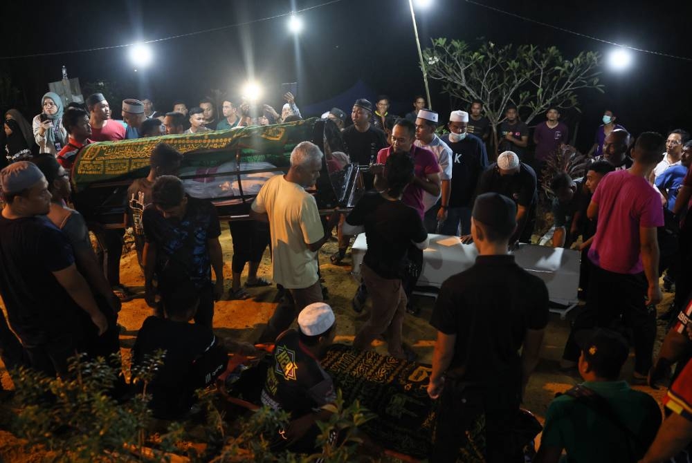 Jenazah tujuh daripada sembilan sekeluarga yang meninggal dunia dalam tragedi kepala air di Jeram Air Putih selamat dikebumikan dalam satu liang lahad di Tanah Perkuburan Islam Felda Lebar Hilir 3 pada malam Selasa. - Foto Bernama