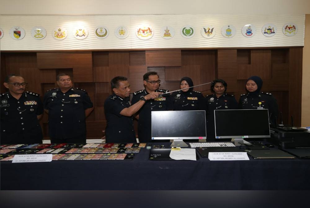 Fisol (tiga dari kiri) menunjukkan barang yang dirampas dari suspek sindiket 'phone scam' di Mergong, Alor Setar dalam serbuan dilakukan pada Isnin.