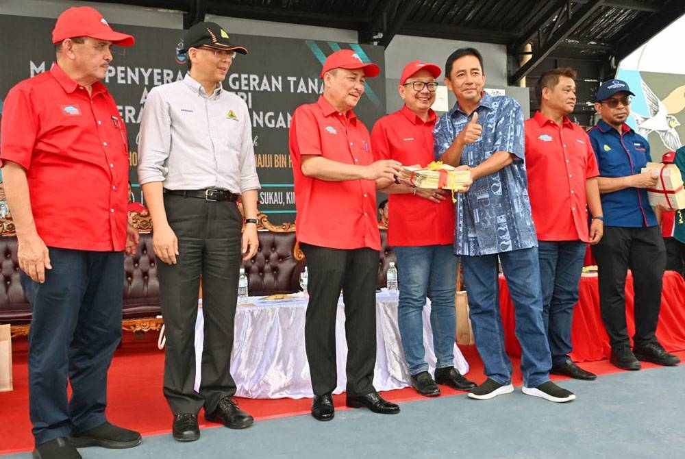 Hajiji (tiga dari kiri) menyerahkan geran tanah kepada wakil penduduk kampung pada Majlis Himpunan Gagasan Rakyat Bahagian Sukau-Lamag di Dataran Pekan Sukau, Kinabatangan.