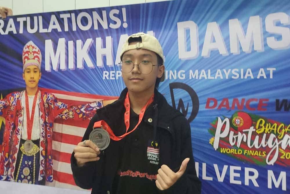 Ahmad Mikhail menunjukkan pingat perak yang diperoleh.