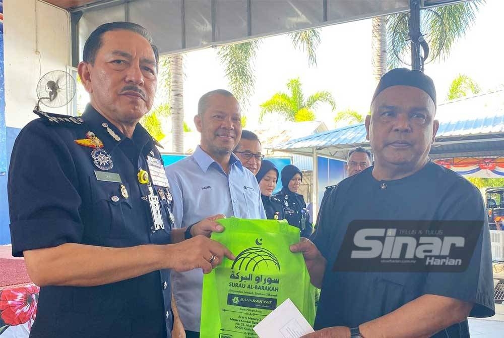 Muhamad Zaki (kiri) bersama Mohamed Al Namiri (dua, kiri) menyampaikan sumbangan kepada pesara polis pada Program Fitrah Aidiladha Bank Rakyat di Kota Bharu pada Ahad.