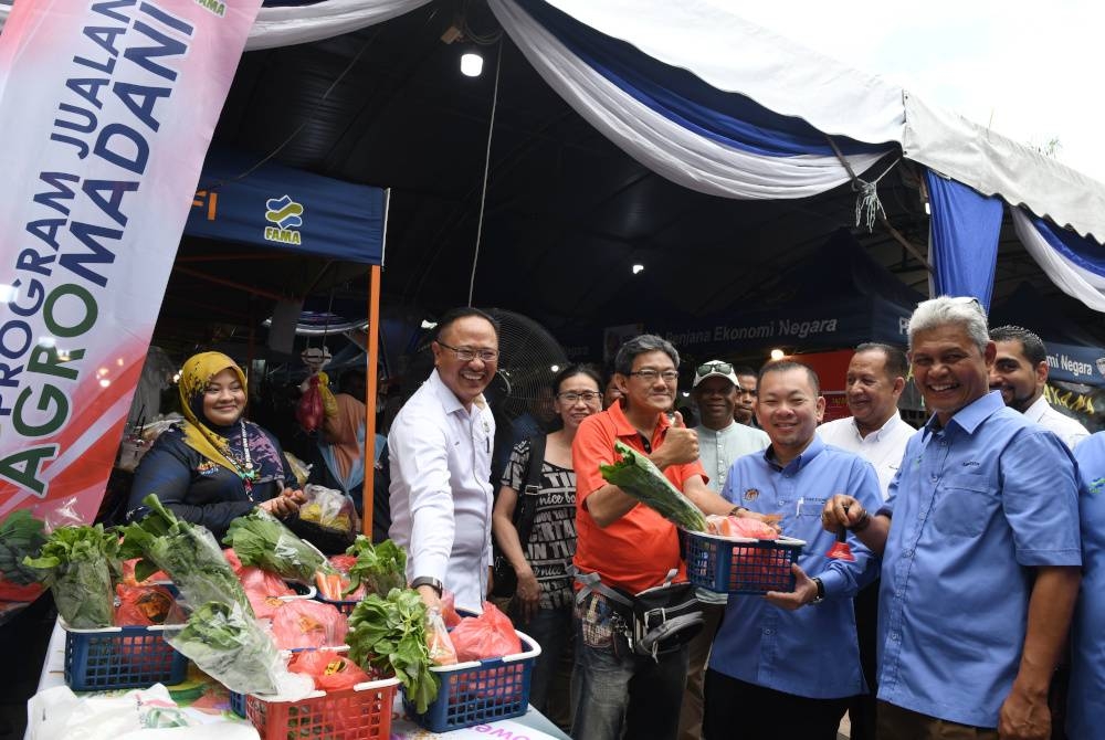 Foon Hin (dua dari kanan) menjual bakul yang mengandungi seekor ayam dan dua jenis sayuran dengan harga RM10 kepada orang ramai semasa hadir majlis perasmian penutup Penang Fama Fest 2023 di pusat membeli-belah Bukit Jambul pada Ahad. - Foto: Bernama