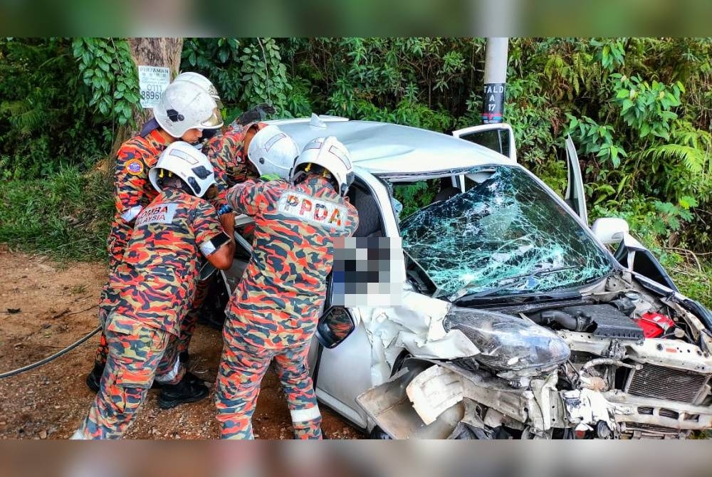 Anggota bomba berusaha mengeluarkan mangsa yang tersepit dalam kenderaan tersebut. - Foto Ihsan JBPM