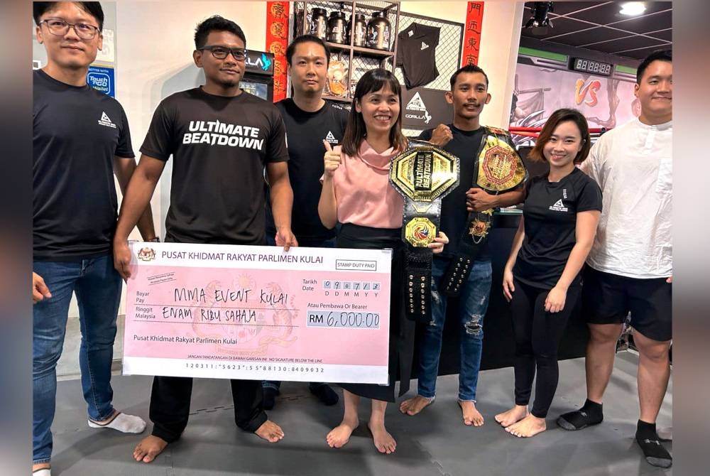 Nie Ching menyampaikan replika cek RM6,000 kepada Mohamad Hisyam (dua, kiri) ketika sesi penyampaian di Ultimate MMA Fitness & Self Defence pada Ahad. - Foto Bernama