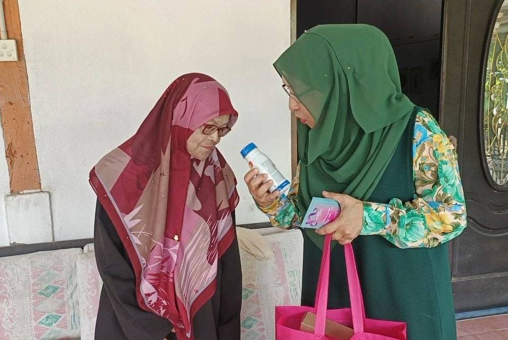 Zuraini (kiri) berkunjung ke rumah Zainah untuk menyampaikan sumbangan di Kampung Tanjung, Kuala Nerang, Padang Terap baru-baru ini.