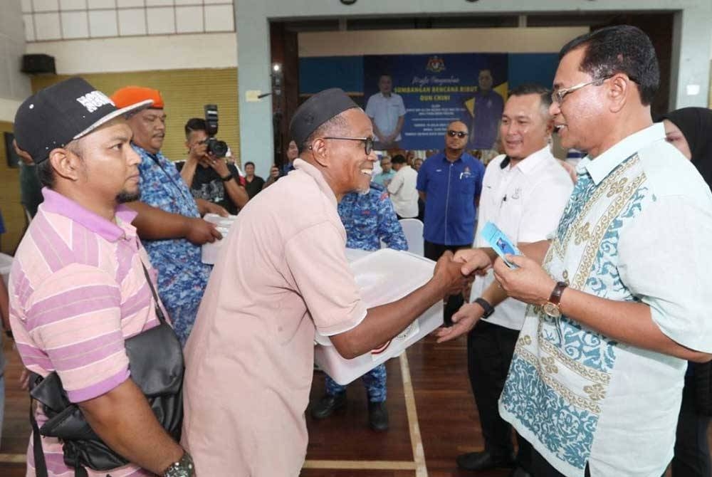 Sh Mohmed Puzi (kanan) menyerahkan bantuan prihatin kepada mangsa ribut.