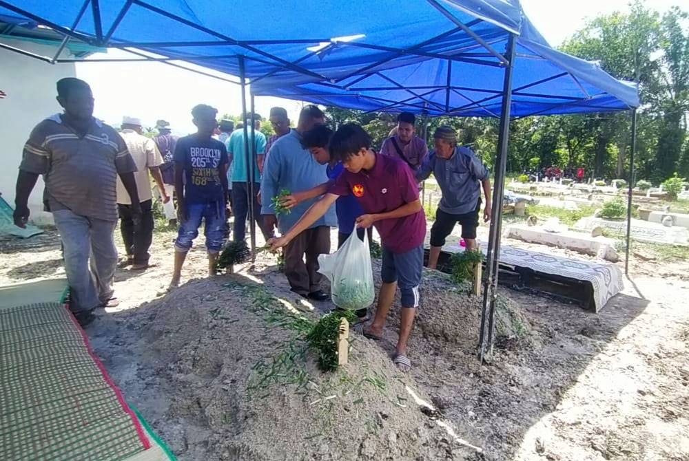 Mohd Ikman Hafifi (kanan) sebaik selesai pengebumian ibu bapanya di Tanah Perkuburan Islam Kampung Serkai Jadi, Tronoh pada Selasa.