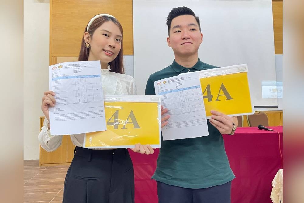 Ray Hong (kanan) dan Sim Yee menunjukkan keputusan STPM 2022 selepas sidang akhbar pada Rabu.