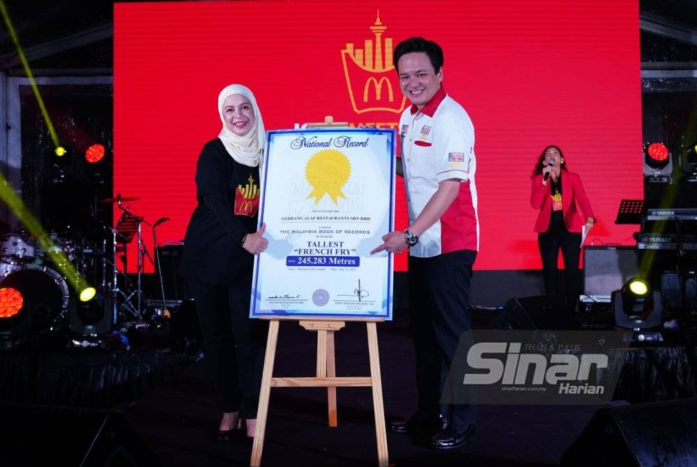 Melati (kiri) menerima replika sijil ‘The Tallest French Fry in Malaysia’ daripada wakil Malaysian Book of Records. - Foto Sinar Harian/MOHD HALIM ABDUL WAHID