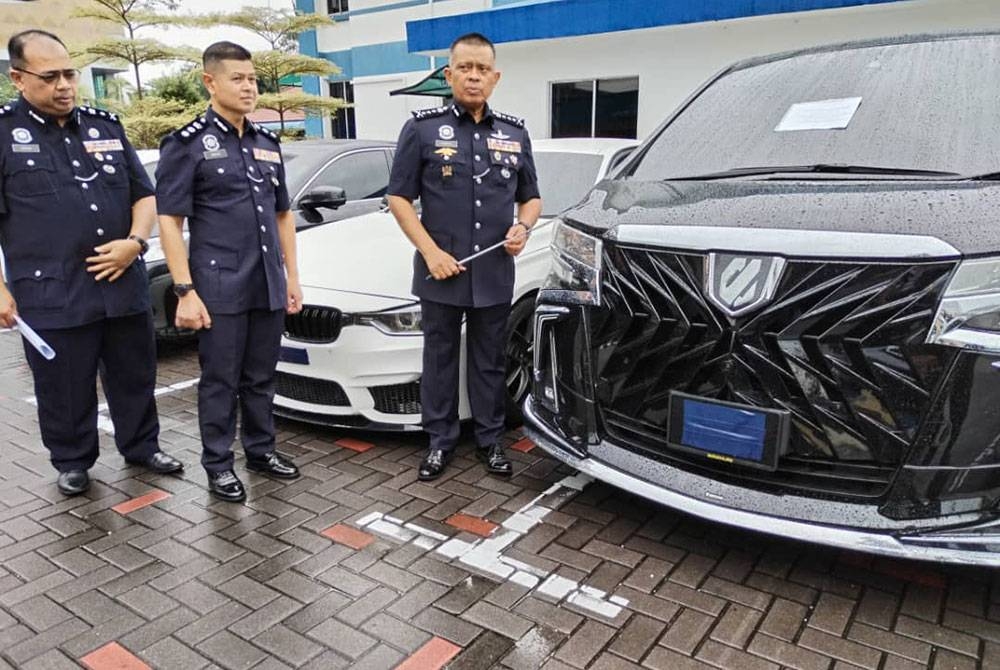 Kamarul Zaman (kanan) bersama sebahagian daripada kenderaan mewah yang dirampas dalam salah satu operasi baru-baru ini.