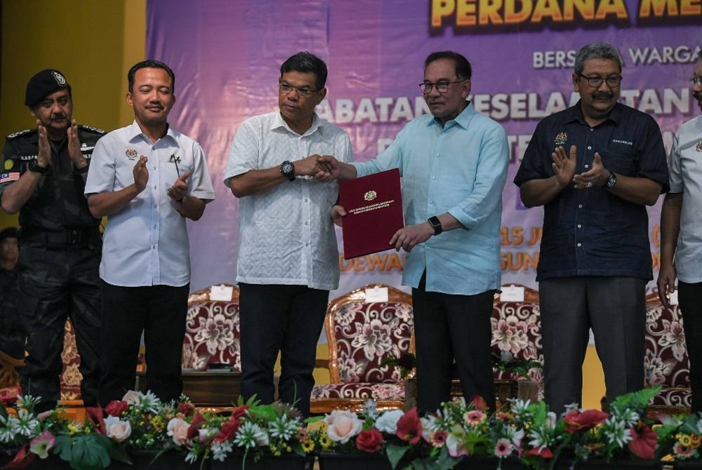 Anwar (dua dari kanan) menyampaikan surat peruntukan kerja-kerja menaik taraf dan pembaikan infrastruktur PGA dan kuarters PDRM kepada Saifuddin Nasution (tiga dari kini) pada majlis Ramah Mesra Bersama Warga Kem Batalion ke-2, PGA PDRM pada Sabtu - Foto Bernama