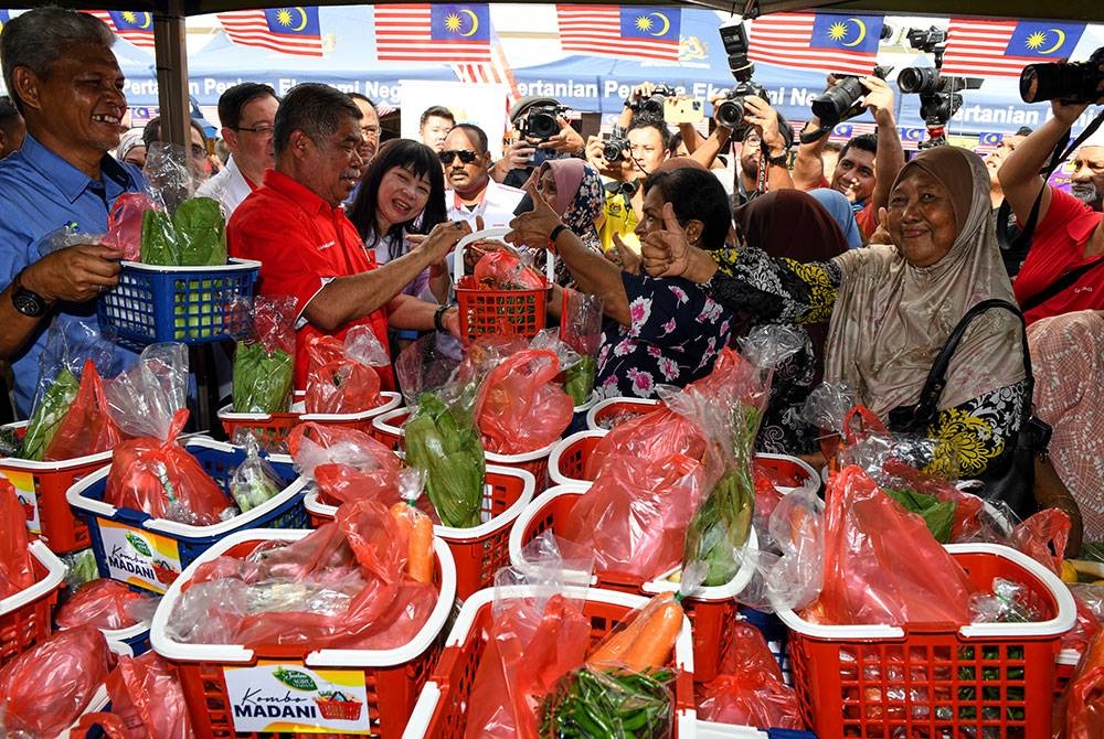 Mohamad (dua dari kiri) cuba menjual seekor ayam bersama sayur-sayuran dengan harga RM10 pada program Jualan Agro Madani@Tanjong di pekarangan Pragin Mall pada Ahad. - Foto Bernama