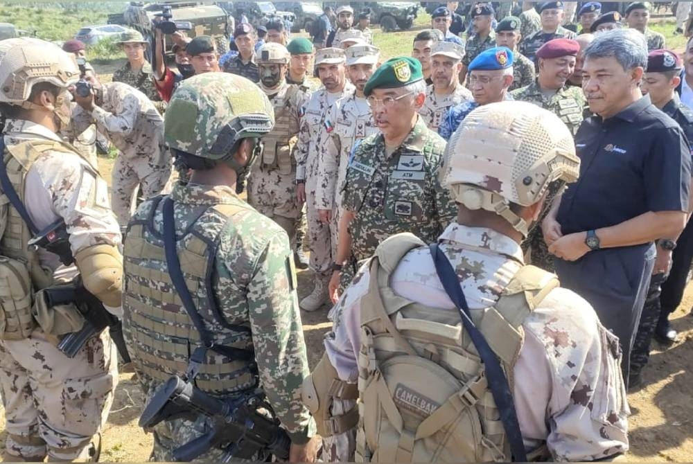 Al-Sultan Abdullah dan Mohamad (kanan) bertanyakan sesuatu kepada anggota TDM dan UAELF selepas Majlis Penutup Eksesais Jungle Falcon Siri 1/2023 di ladang sawit Felda Panching Selatan, Kuantan pada Ahad.