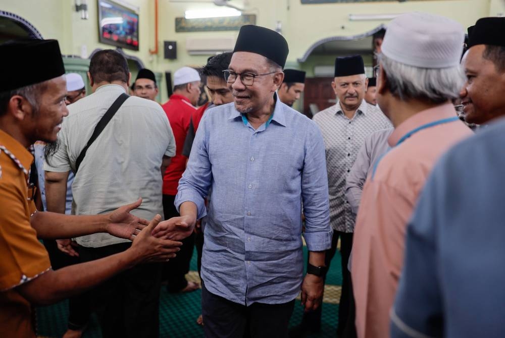 Anwar bersalaman bersama jemaah selepas menunaikan solat Zohor pada Majlis Peluncuran Pembangunan Masjid Lama Sungai Bakap, Seberang Perai Selatan hari ini. - Foto Bernama